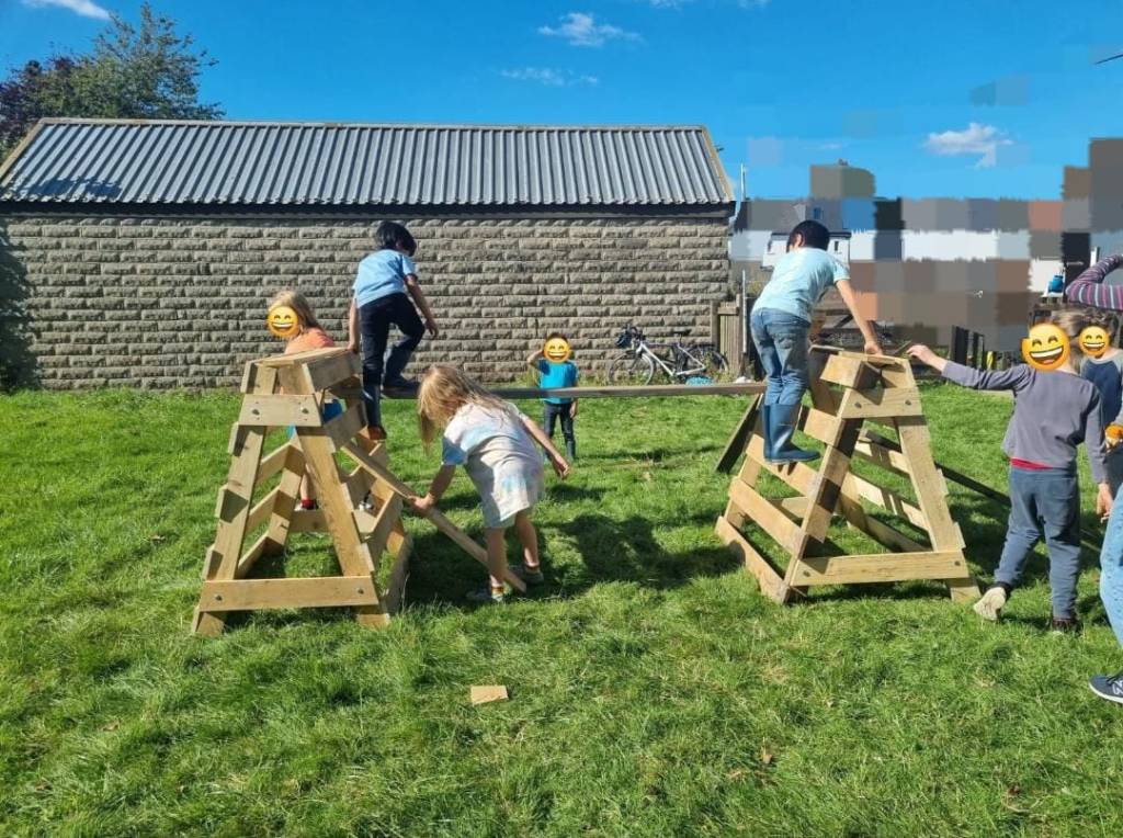 kids (anonymised) climbing on the frames they built with pallets and planks